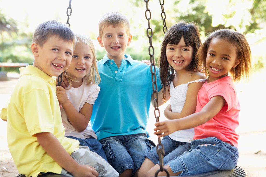 group of kids sitting on tire swing