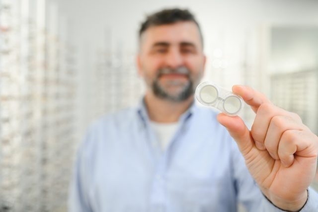 Man holding contact eye lenses and container