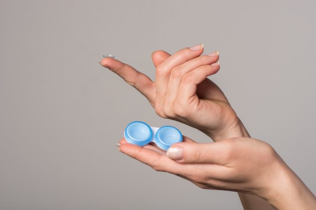 Soft contact lens and blue container in female hands