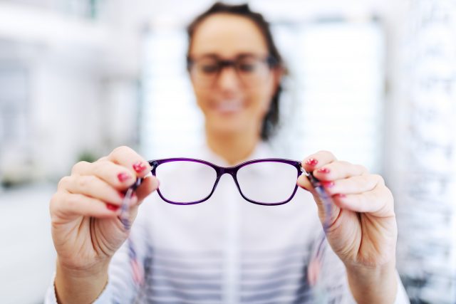 Woman at optician holding eyeglasses she want to buy
