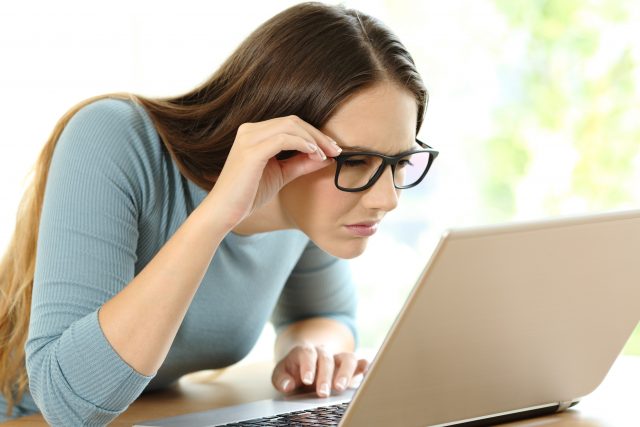 woman struggling to see laptop screen