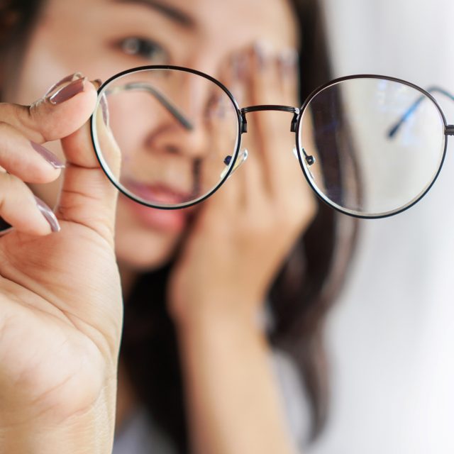 woman hand holding eyeglasses with eye pain