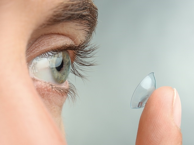 man holding contact lens to eye