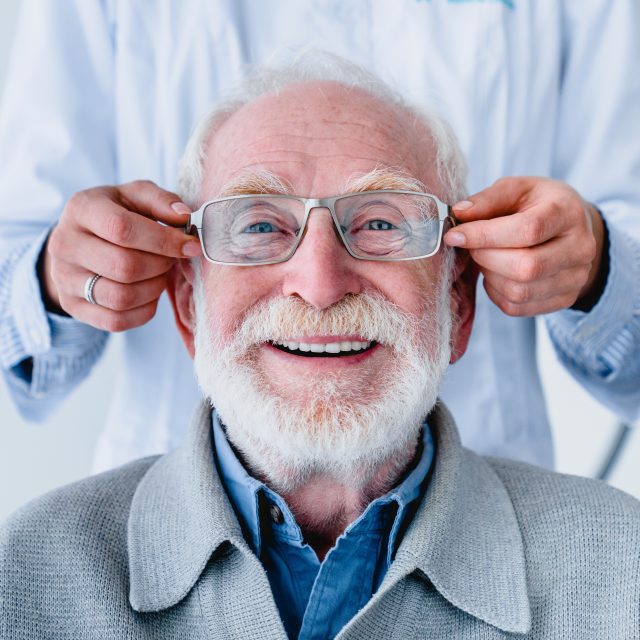 fitting glasses on cheerful senior man