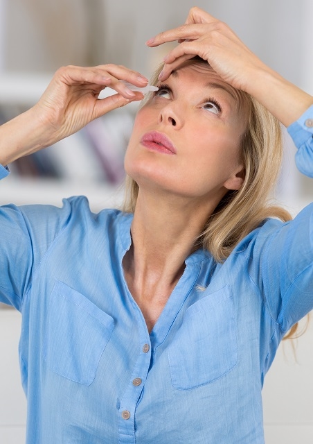 woman putting eye drops in her eye
