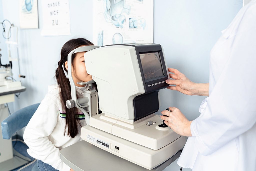 young girl behind eye exam equipment