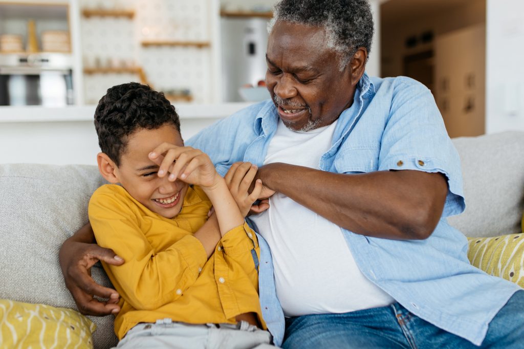 grandfather tickling grandson at home