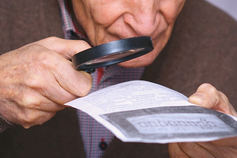 man with low vision reading with magnifying glass