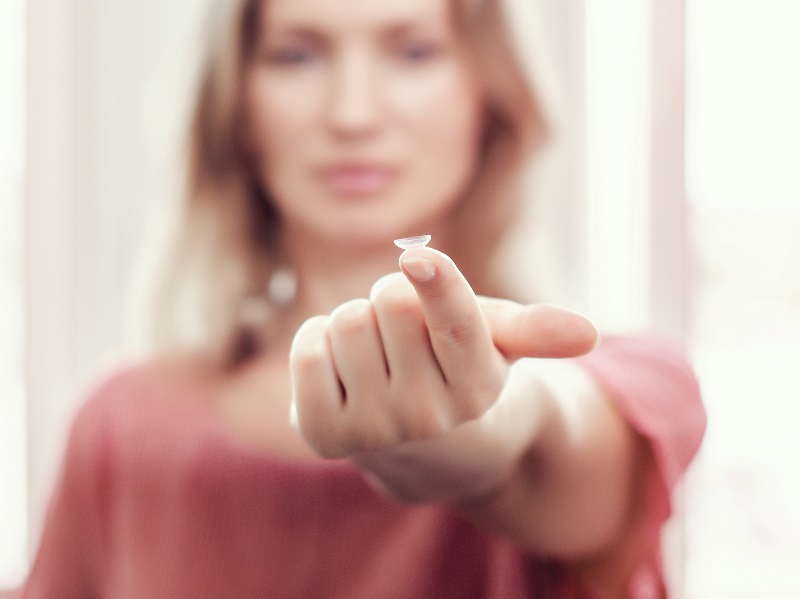 woman hodling contact lens on finger
