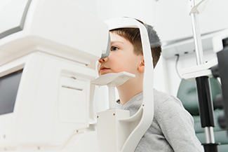 Eye doctor examines eyesight of young caucasian boy in eye ophthalmological clinic