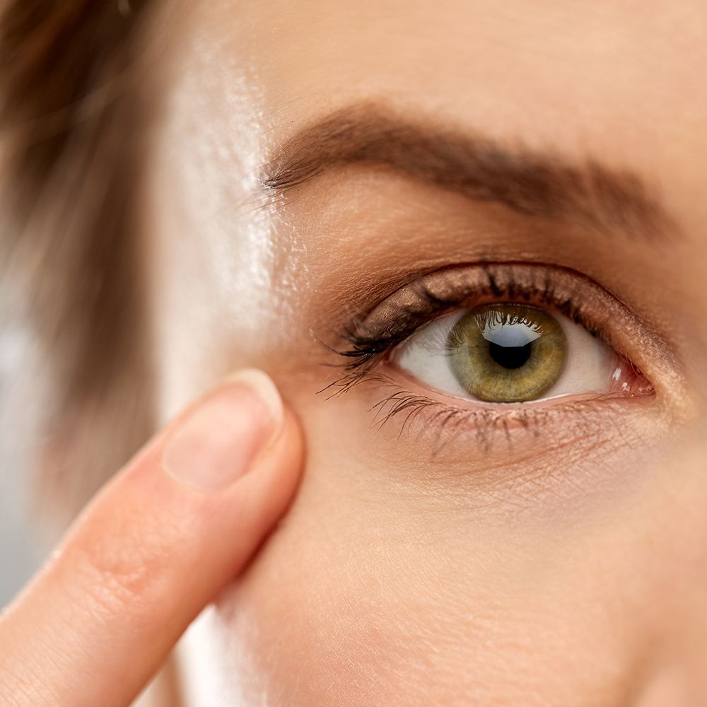 Middle aged caucasian woman pointing finger to eye wearing contact lens
