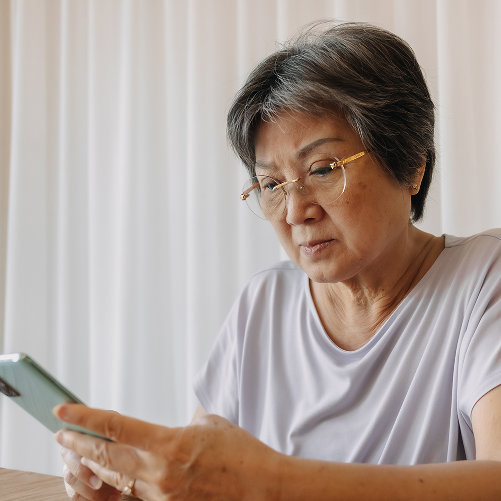 Older Asian woman looking through mobile phone