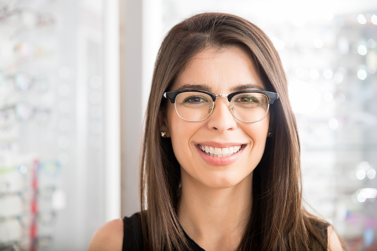 Smiling latin woman trying new eyeglasses for daily purpose in optical store