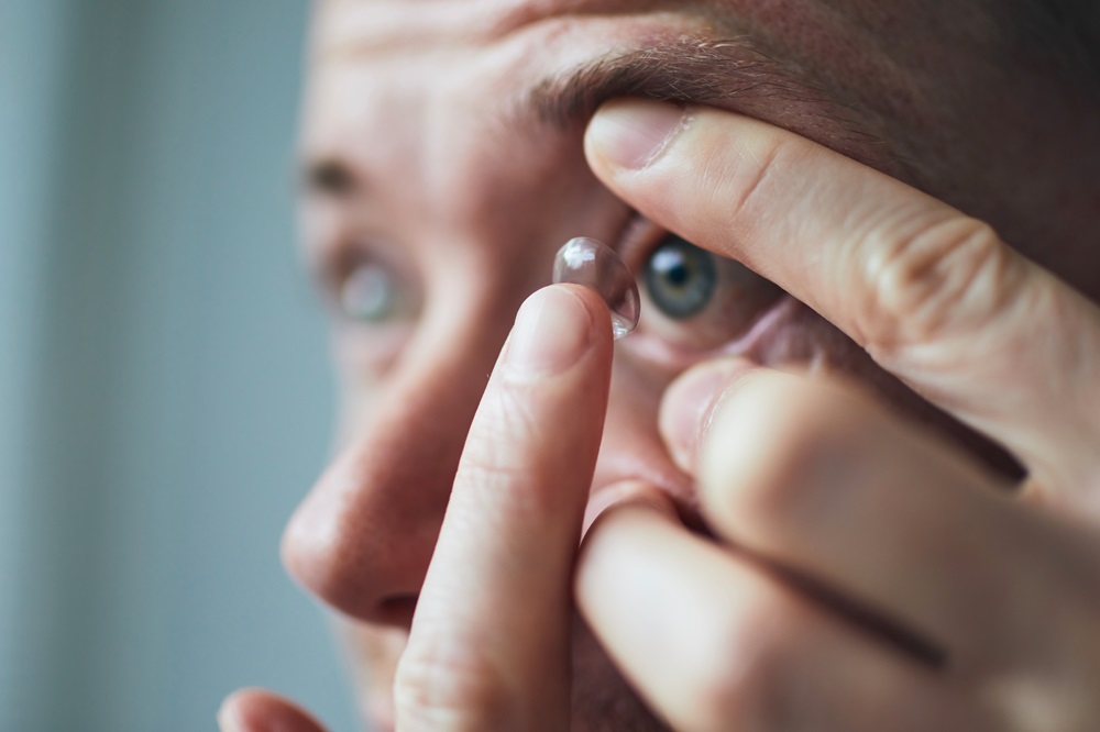 Young man putting contact lens on eye