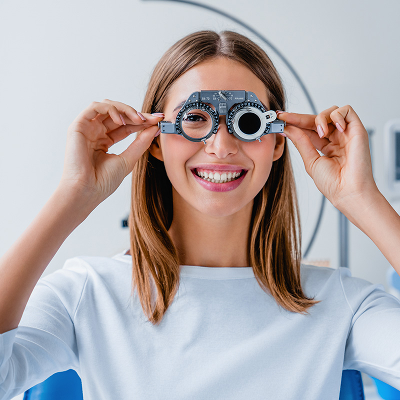 Young woman checking vision with eye test glasses during a medical examination at the ophthalmological office