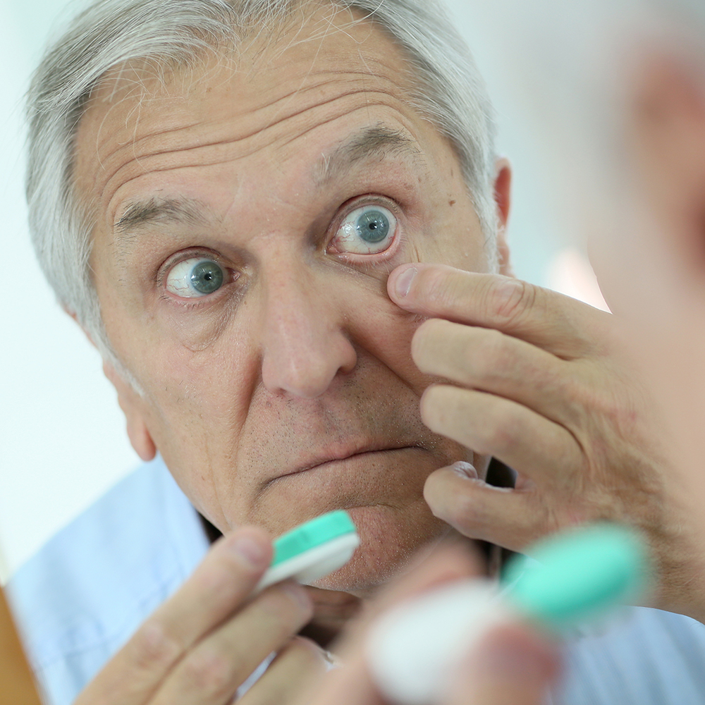 Man applying contact lens in mirror