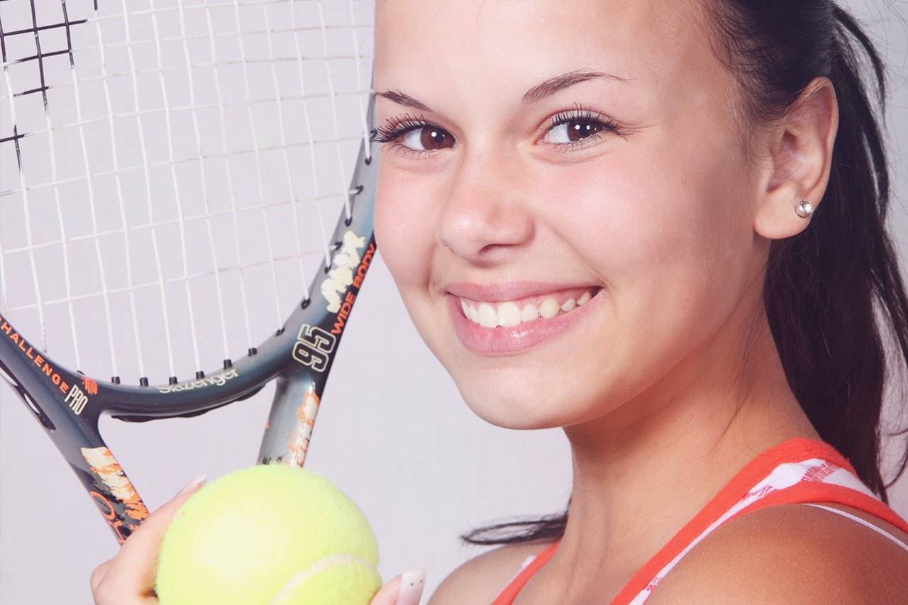 young girl holding tennis racket and ball