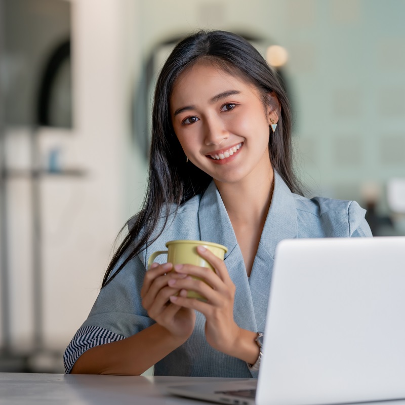 young woman sitting at laptop with coffee