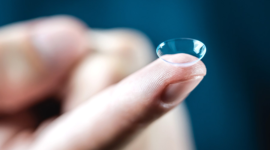 Contact lenses macro close up. Man holding lens on finger.