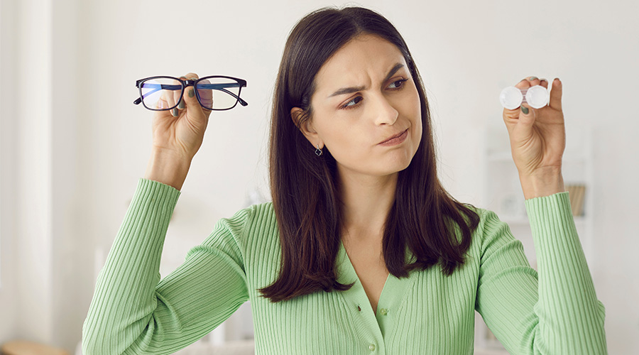 Portrait of pensive woman hesitating choosing between glasses and contact lenses.