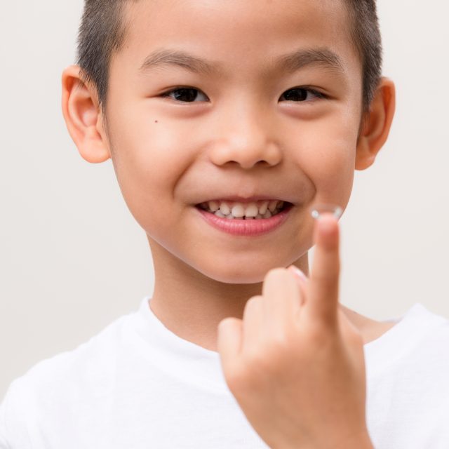 boy holding contact lens on finger