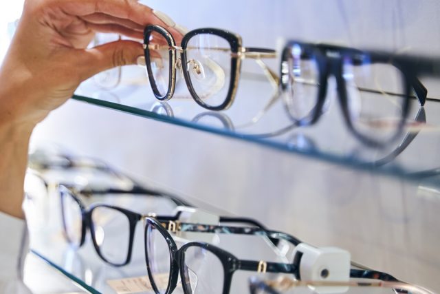 Optician comparing spectacles with client