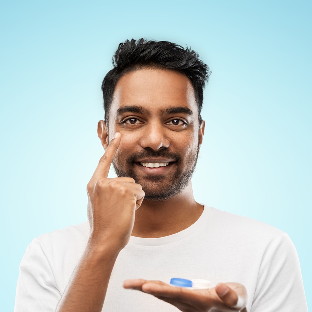 Young indian man applying contact lenses