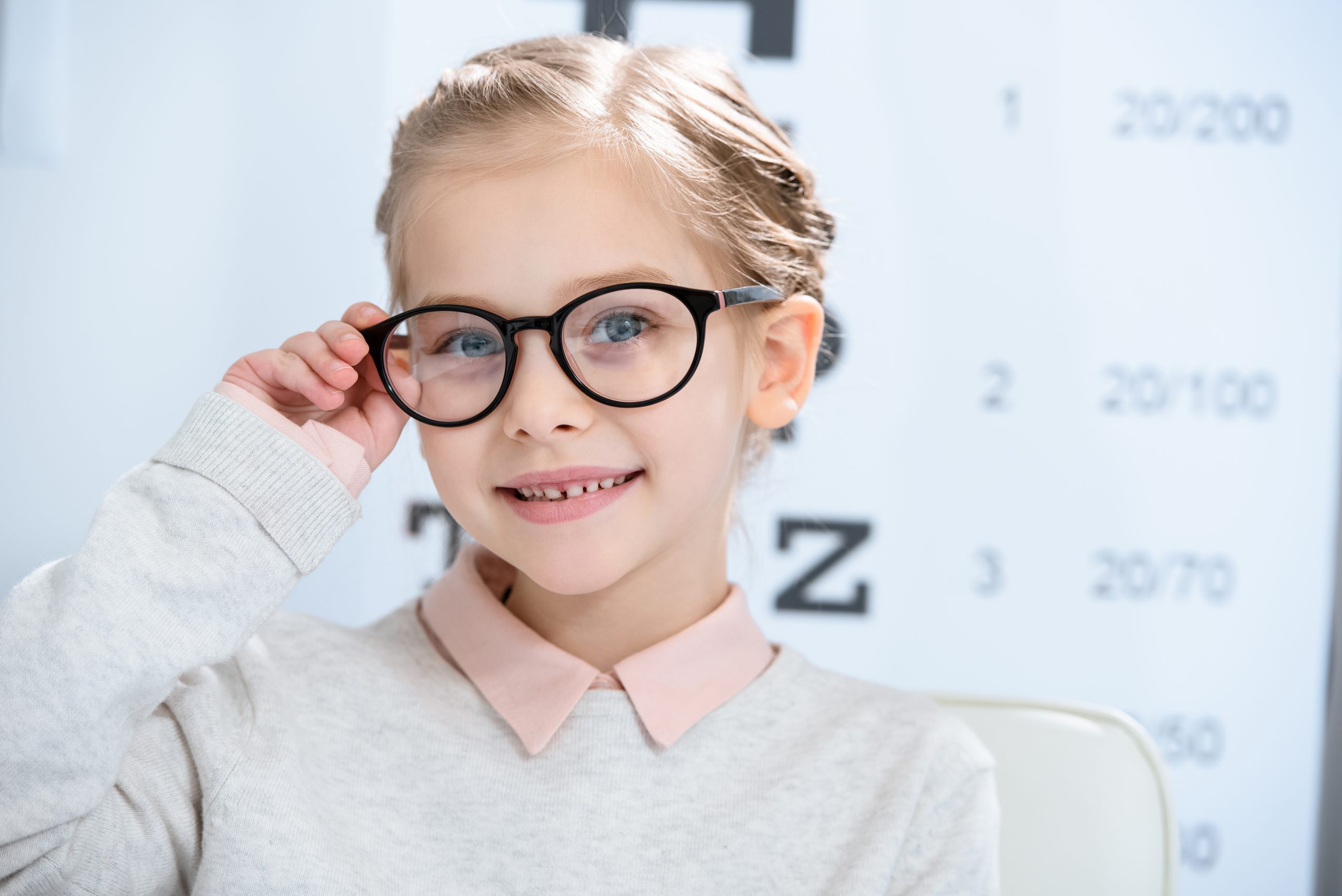 Child looking at camera in glasses at oculist consulting room