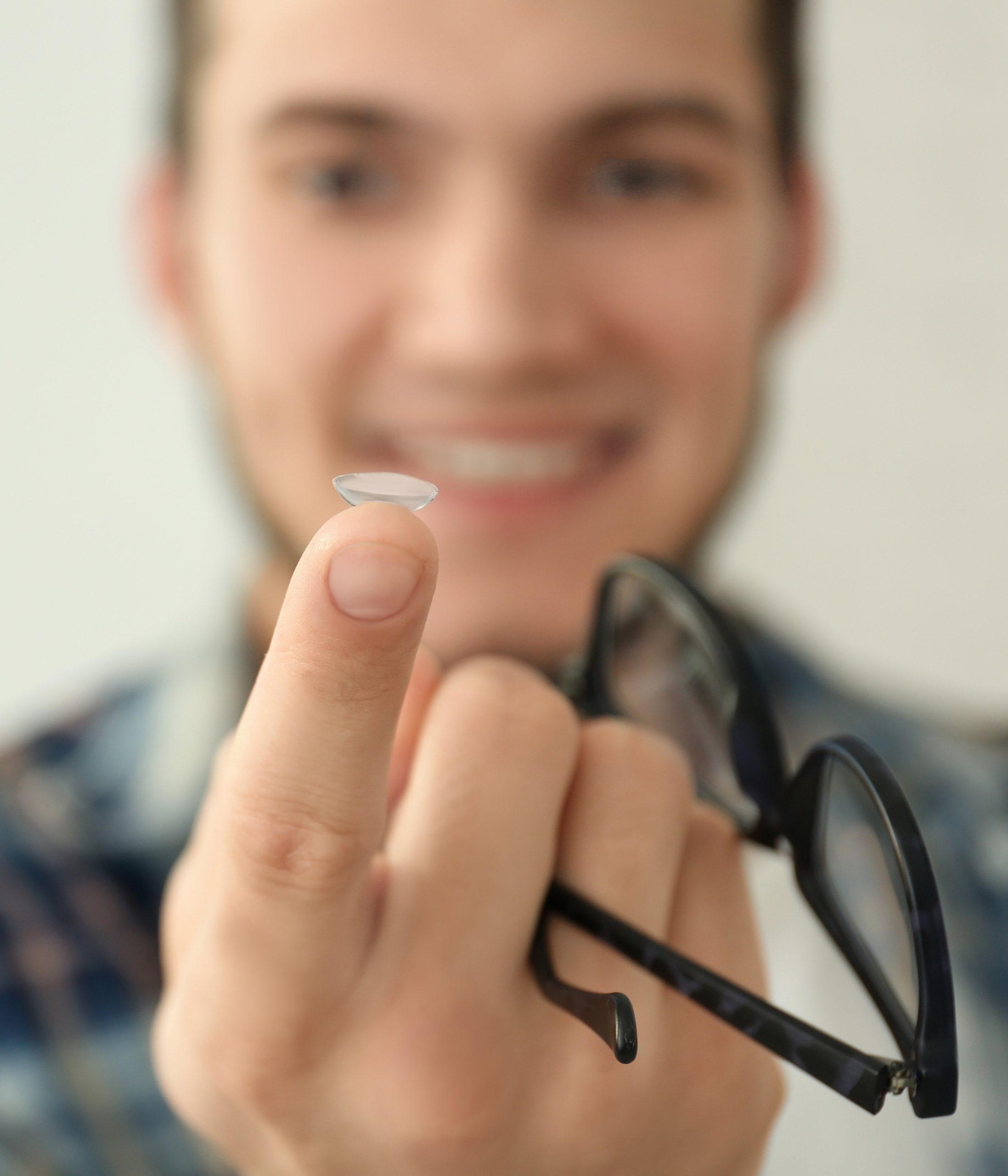 Man holding contact lens and glasses closeup scaled