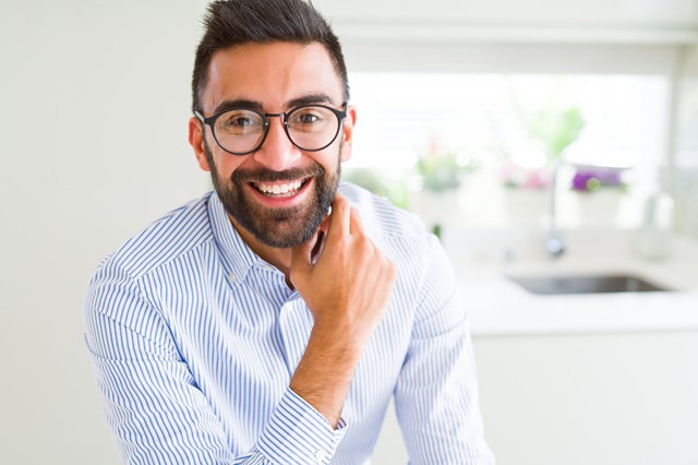 Business man wearing glasses and smiling cheerful with confident smile on face