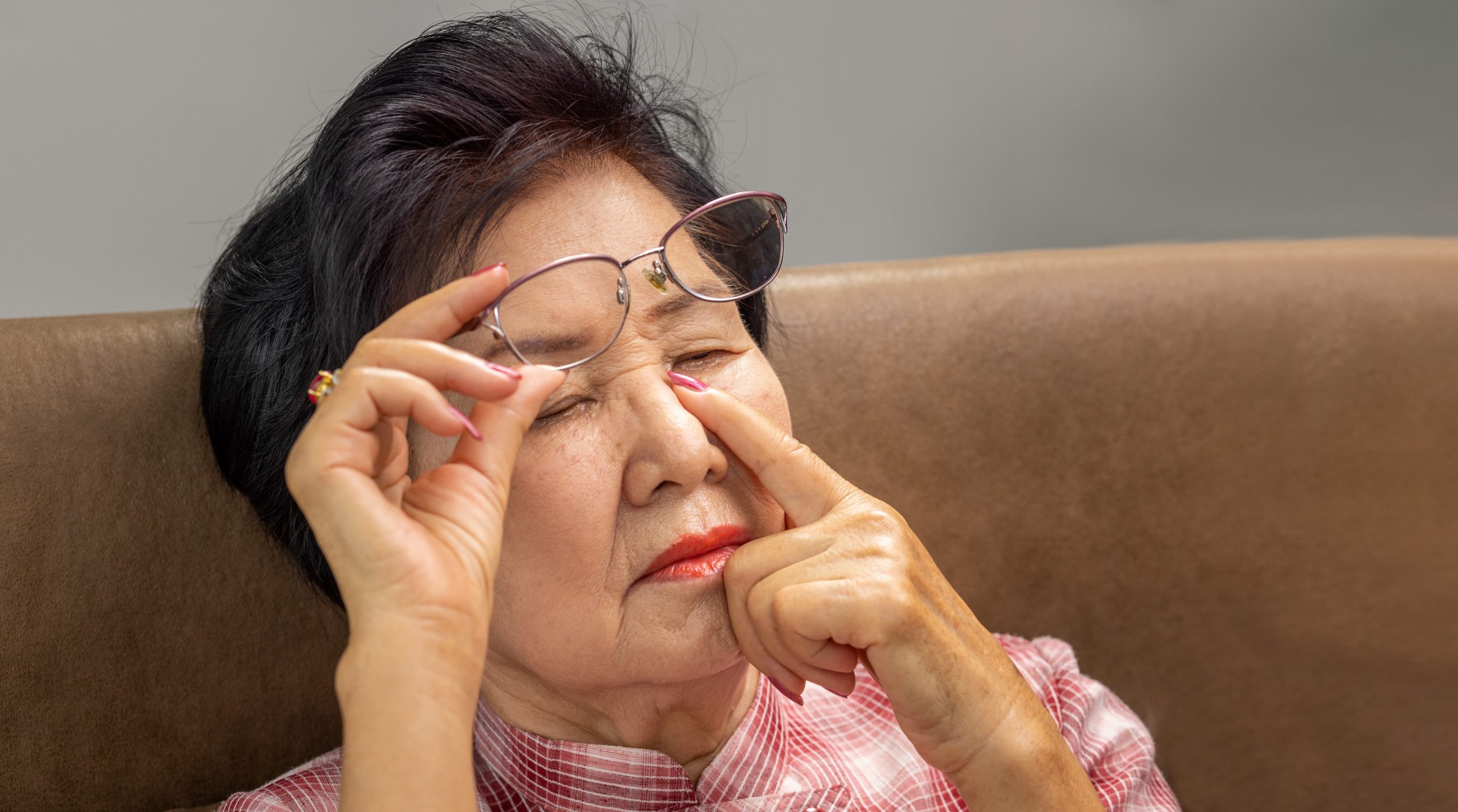 Asian senior older woman taking off glasses