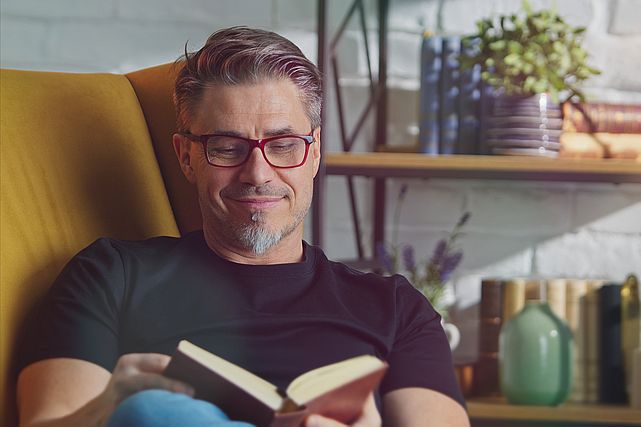 man wearing glasses and reading a book