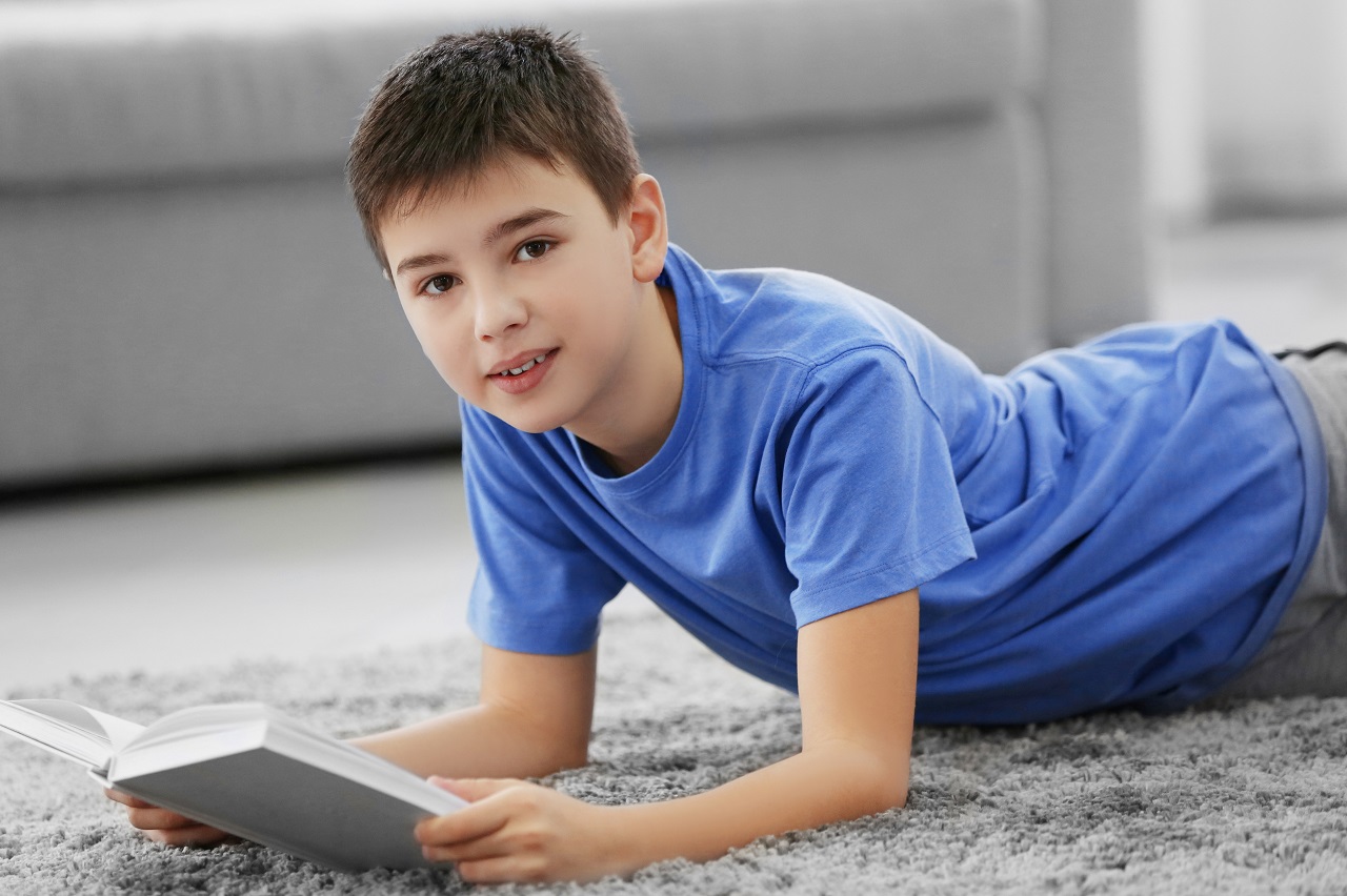boy reading book on a floor at home