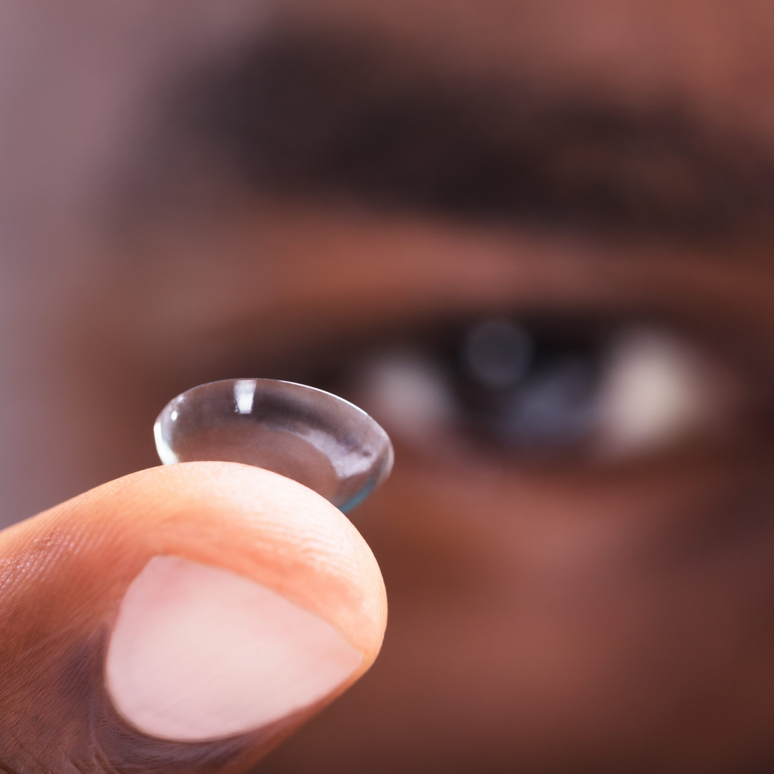 Close up Of A Man Holding Transparent Contact Lens In His Finger