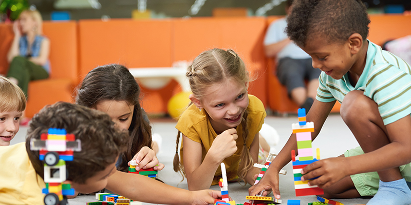 Group of funny kids playing with block toys indoor. Cute kids playing together indoor. Preschool early education.