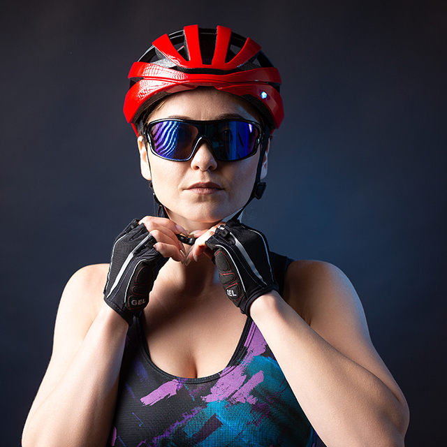 A young caucasian female cyclist wearing a safety helmet and glasses