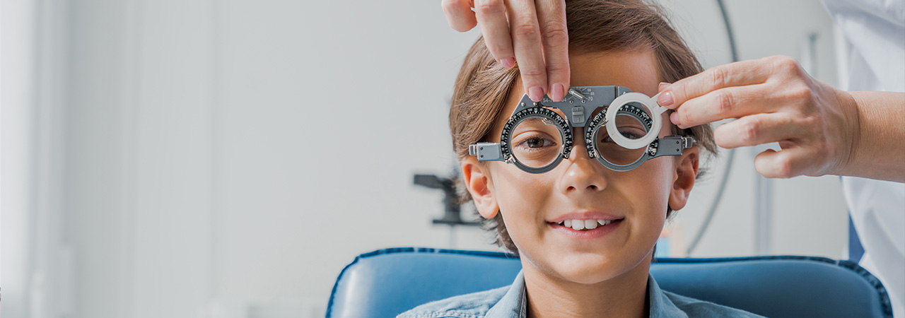 Child boy in glasses checks eye vision at pediatric ophthalmologist