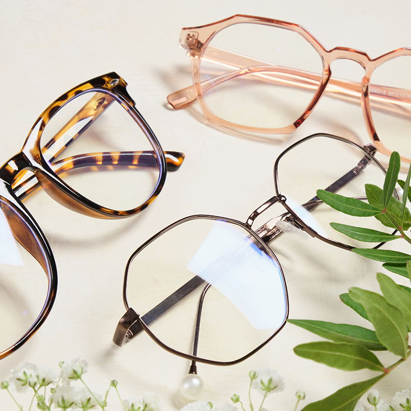 several fashionable glasses and flowers on a beige background copy space top view