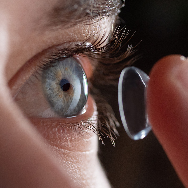 Close up of a man putting contact lenses on blue eye