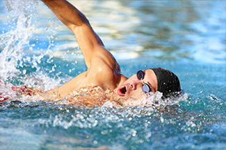 Man swimmer swimming crawl in blue ocean open water.
