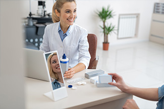 Smiling ophthalmologist in white lab coat prescribing contact lenses for patient