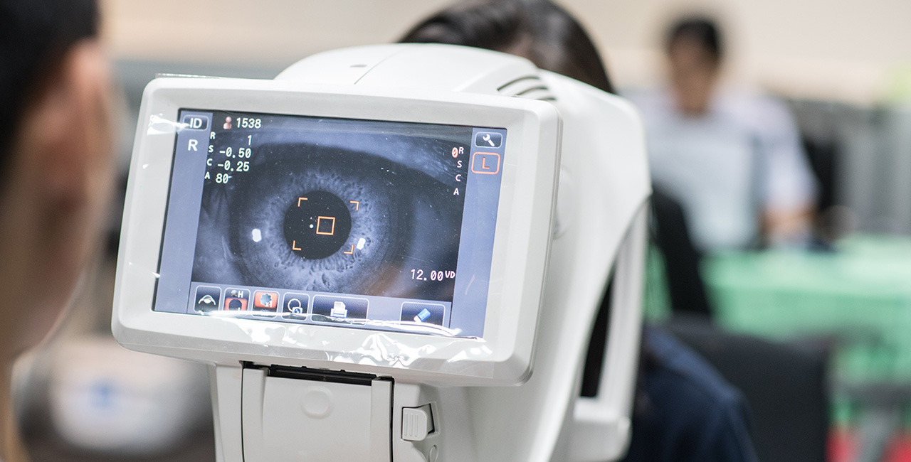Woman looking at refractometer eye test machine in ophthalmology