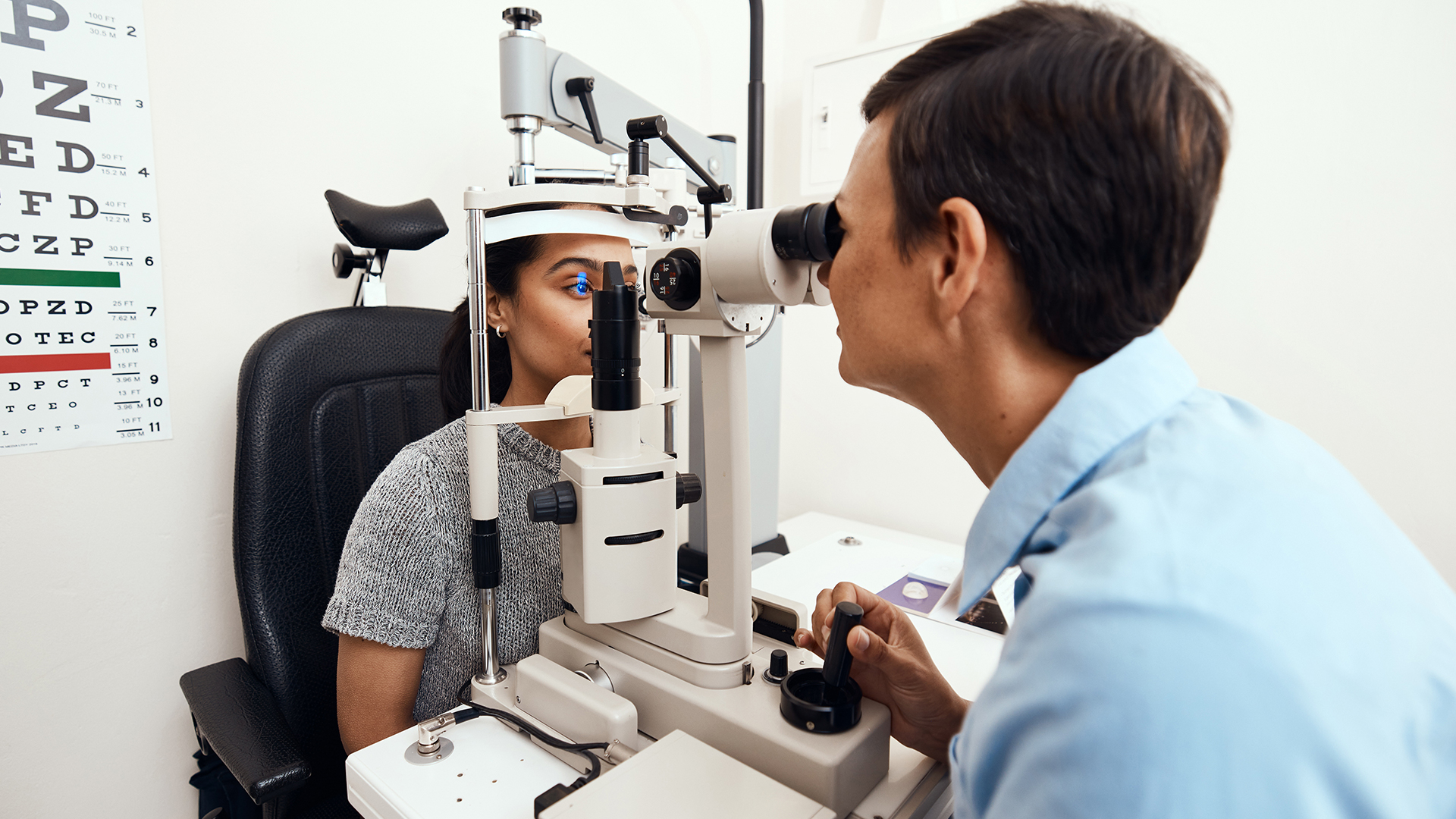 middle aged caucasian ophthalmologist and hispanic female patient using an ophthalmoscope