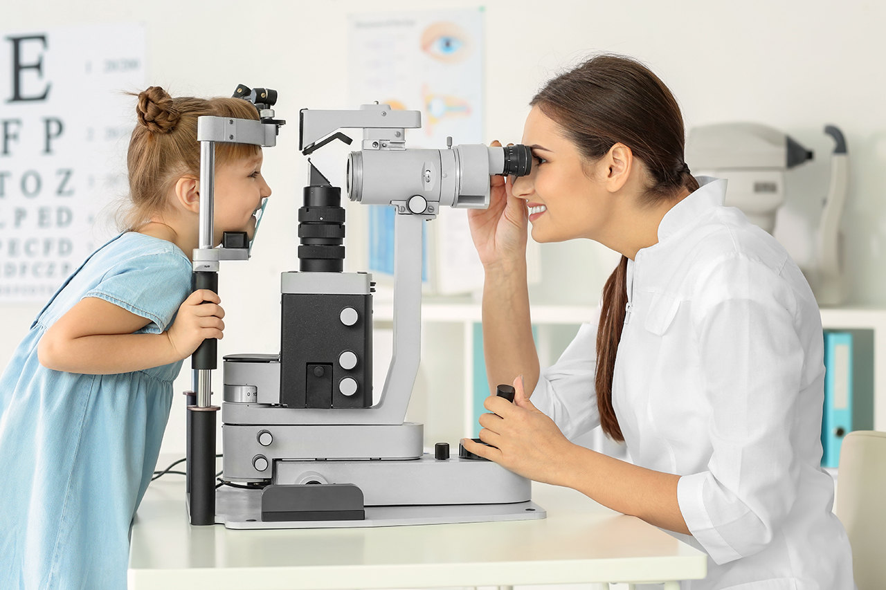 optometrist testing little girls eye