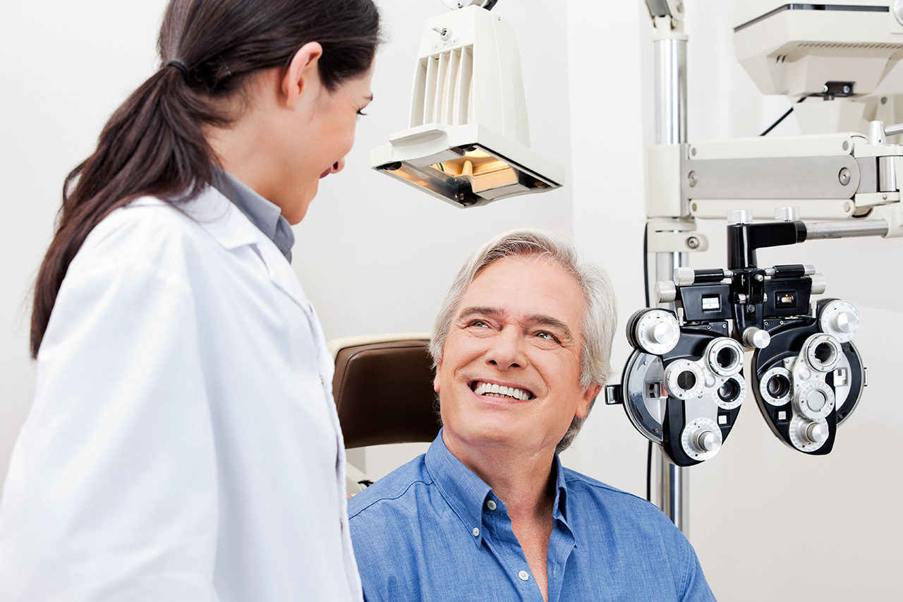 senior male eye exam patient smiling at younger female optometrist