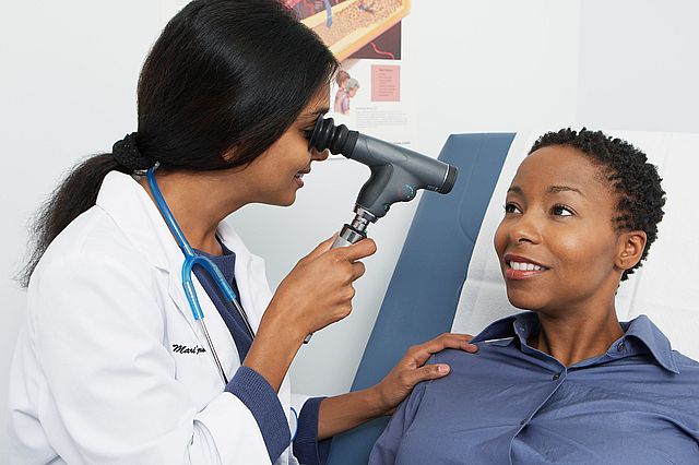 An optometrist checking a females eye with an eye testing equipment