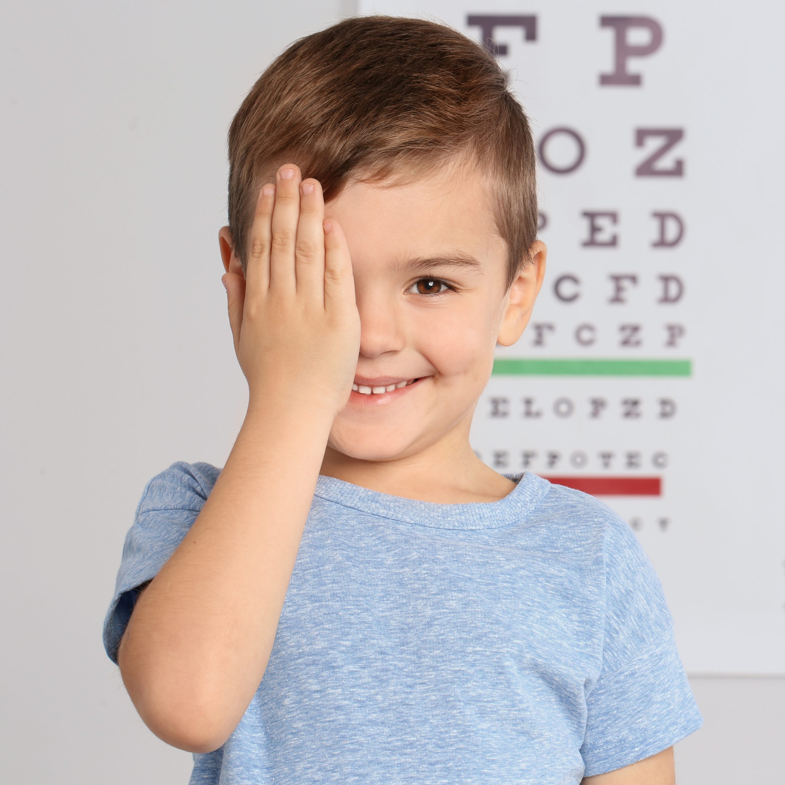 happy young boy covering eye with hand