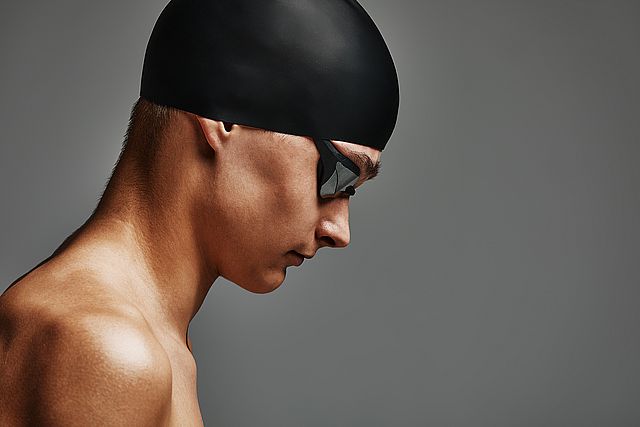 Face of a man swimmer close up, gray background, copy space, young guy swimmer in a mask and swimming cap