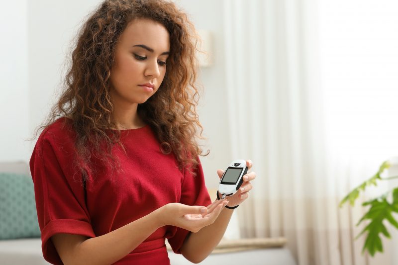 woman using digital glucometer at home