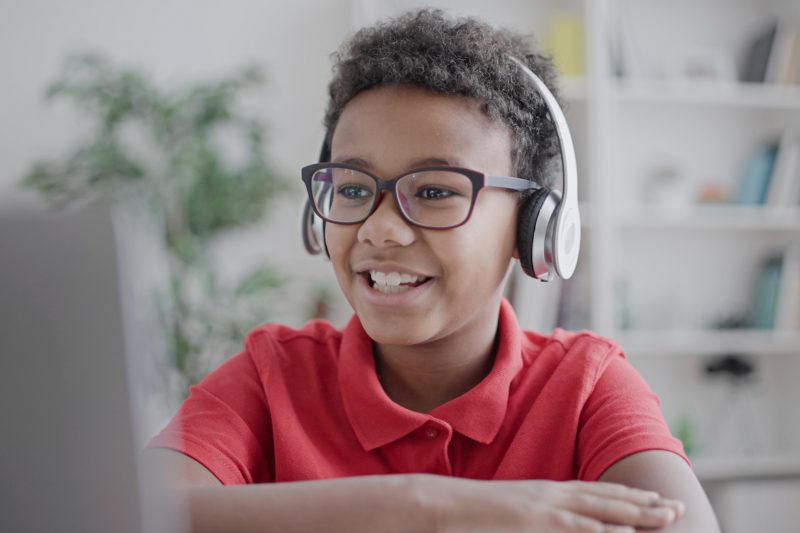 child in headphones looking at laptop rev
